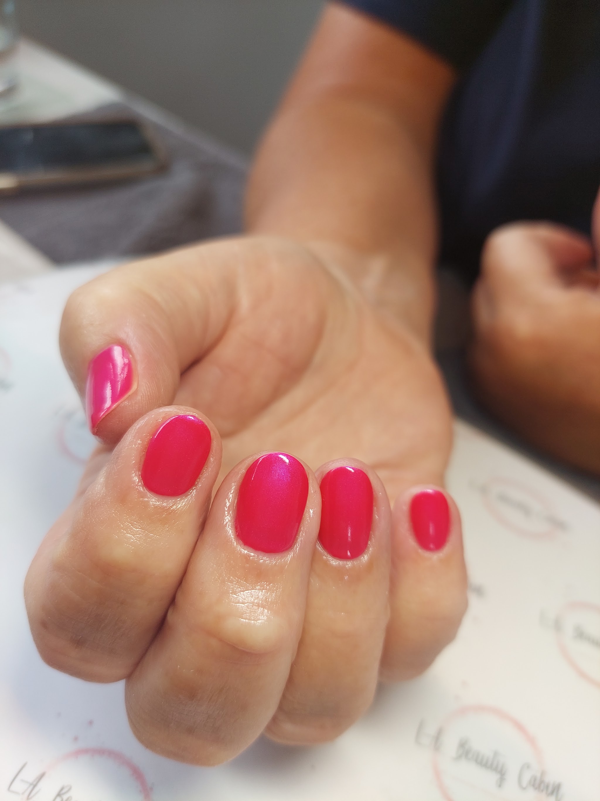Glossy bright pink nails photographed at the cabin