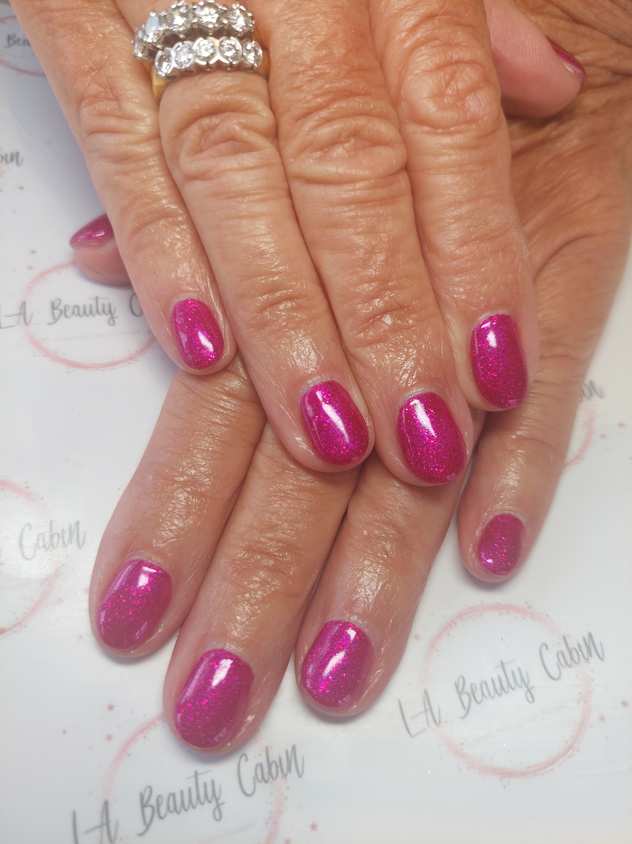 A finished set of bright magenta glitter nails